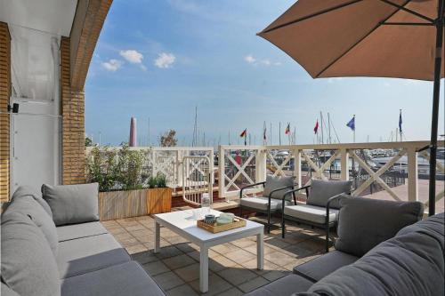 a patio with couches and a table and an umbrella at Kabbelaarsbank 503 - Port Marina Zélande in Ouddorp