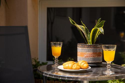 a table with a plate of bread and two glasses of orange juice at Eden - A Night near Athens Int Arpt in Spáta