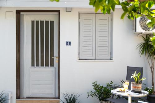 a white house with a door and a table at Eden - A Night near Athens Int Arpt in Spáta