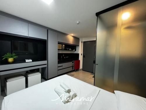 a bedroom with a bed and a large screen tv at Get By Side - Jardim Oceania in Tambaú