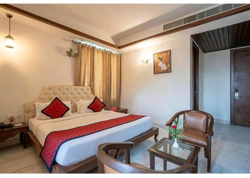 a bedroom with a large bed and a chair at Hotel Agra Grande By Goyal Hoteliers in Agra