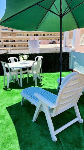 a table and chairs with an umbrella on the grass at Fuengirola Casa Centro Mar y Sol in Fuengirola