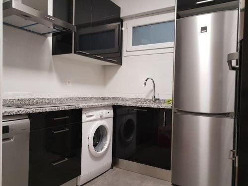 eine Küche mit einem Kühlschrank aus Edelstahl und einer Waschmaschine in der Unterkunft Donosti House con Parking ESS in San Sebastián
