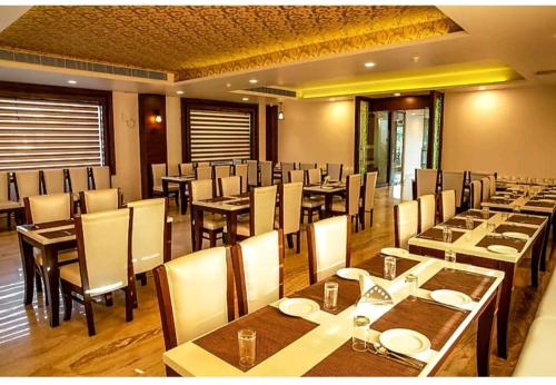 a dining room with tables and chairs in a restaurant at Hotel Agra Grande By Goyal Hoteliers in Agra