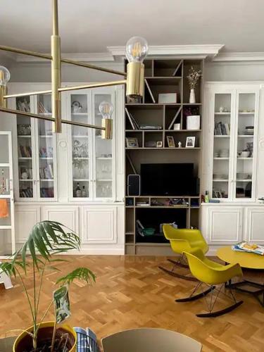 un salon avec des chaises jaunes et une télévision dans l'établissement Stunning family Flat at the very heart of Paris, à Paris