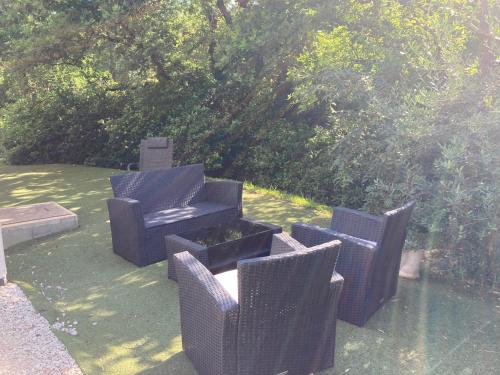 - un groupe de chaises en osier et une table dans la cour dans l'établissement Bastide du Safrus, à Villeneuve-lès-Avignon