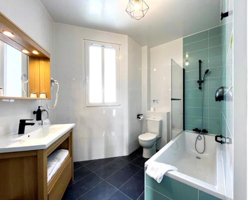 a bathroom with a tub and a toilet and a sink at Hôtel Odessa Montparnasse in Paris
