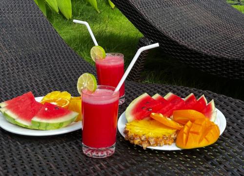 a table with a plate of fruit and two glasses of juice at Ocean View tourist guest house at Negombo beach near the airport in Negombo