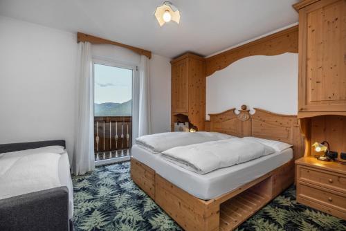 a bedroom with two beds and a large window at Hotel Tirol- Natural Idyll in Montesover