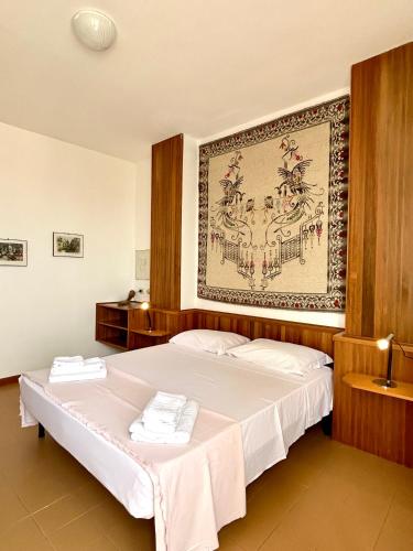 a bedroom with a large bed with a painting on the wall at NURAS - Penthouse Antonietta with view in Alghero