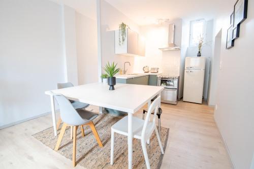 - une cuisine avec une table et des chaises blanches dans la chambre dans l'établissement « AU VINCI VERT » Appartement 4 pers. NEUF, à Amboise