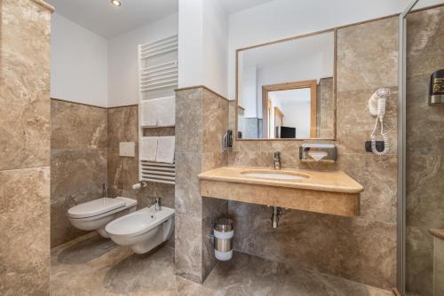 a bathroom with a sink and a toilet and a mirror at Hotel Tirol- Natural Idyll in Montesover