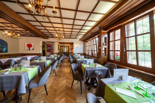 a dining room with tables and chairs and windows at Hotel Munsch Restaurant & Wellness, Colmar Nord - Haut-Koenigsbourg in Saint-Hippolyte