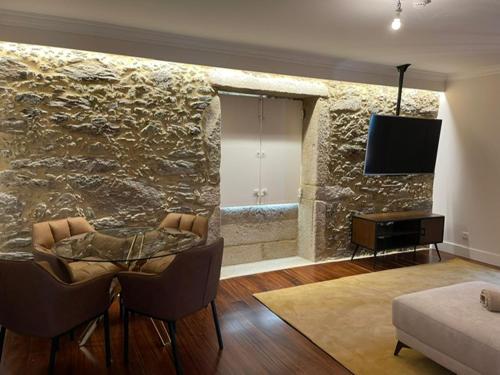 una sala de estar con una pared de piedra con mesa y sillas. en Quinta das Fontes, en Poças do Monte