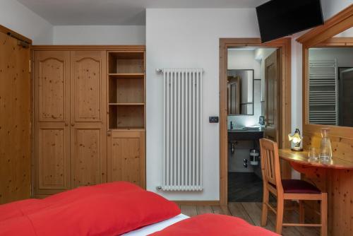 a bedroom with a red bed and a radiator at Hotel Tirol- Natural Idyll in Montesover