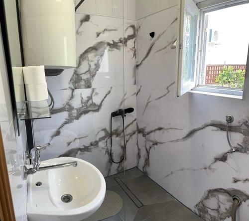 a white bathroom with a sink and a window at Apartments AS in Budva