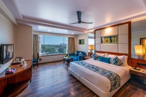 a hotel room with a large bed and a tv at Libra Lords Inn, Jaipur in Jaipur