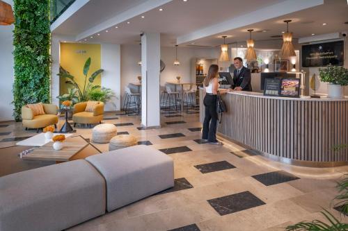 a man and woman standing at a bar in a lobby at Hotel SERHS Del Port in Barcelona