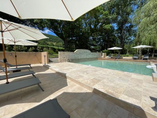 une piscine avec des chaises et des parasols à côté d'une piscine dans l'établissement Les terrasses du durzon, à Nant