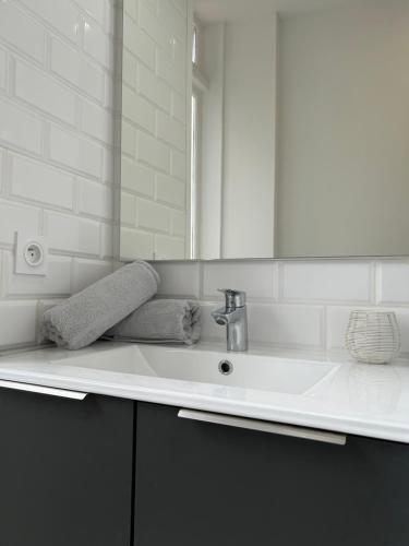 une salle de bain blanche avec un lavabo et un miroir dans l'établissement Le Toulousain 201 - Appartement Cosy en Hypercentre - Quartier Jeanne d'Arc, à Toulouse