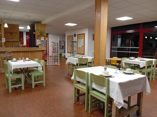 une salle à manger avec des tables blanches et des chaises vertes dans l'établissement Olydea Vorey-sur-Arzon, à Vorey