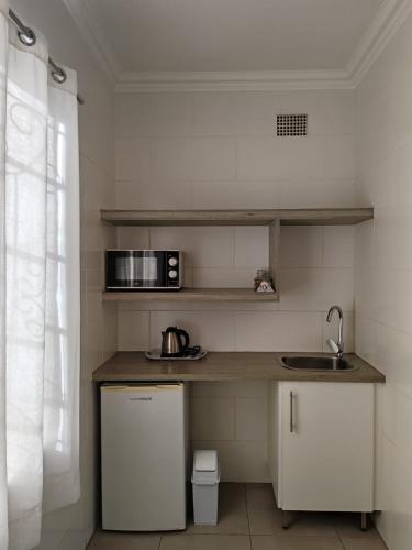 a small kitchen with a sink and a microwave at LA Guesthouse in Piet Retief