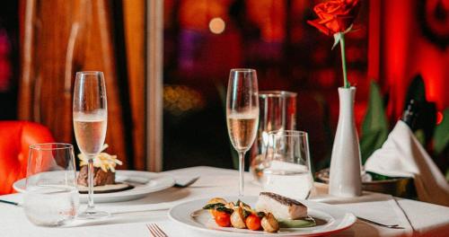 a table with two plates of food and wine glasses at DPNY Beach Hotel & SPA Ilhabela in Ilhabela