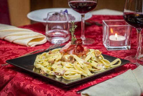 a plate of pasta on a table with a candle at Hotel Tirol- Natural Idyll in Montesover