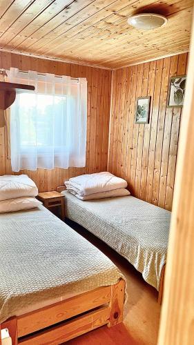 a bedroom with two beds in a wooden cabin at Dobra Miejscówka Domki nad Jeziorem Solińskim Jacuzzi 60 m od plaży 504-978-418 in Zawóz