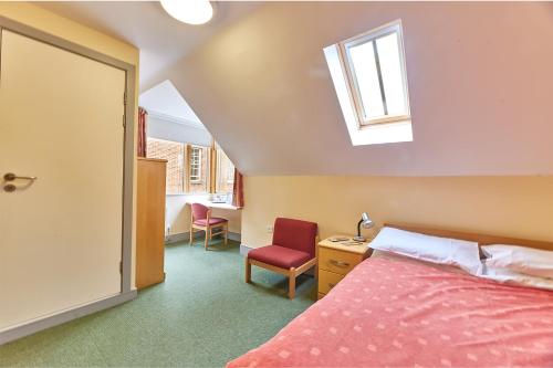 a bedroom with a bed and a window and a chair at St John's College in Durham