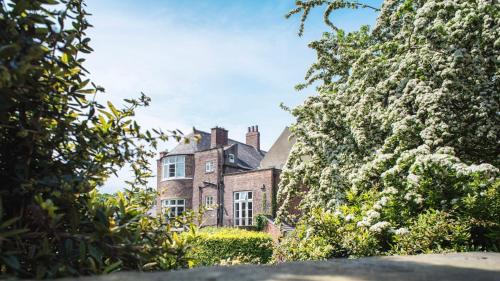 an old brick house with trees in the foreground at St John's College in Durham