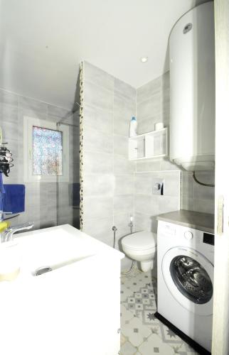 une salle de bain avec machine à laver et toilettes dans l'établissement Les 2 dauphins, au Barcarès