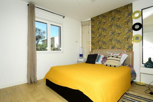 a bedroom with a bed with a yellow blanket at Les 2 dauphins in Le Barcarès