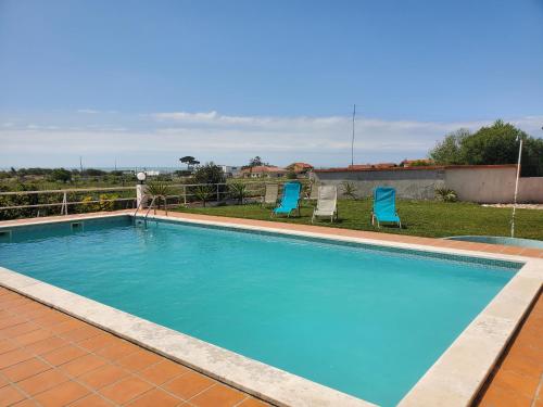 a swimming pool with two blue chairs in a yard at Casamilia Suite Parentale in Esposende