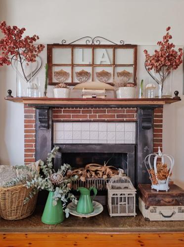 a fireplace with flowers and vases on a table at LA Guesthouse in Piet Retief