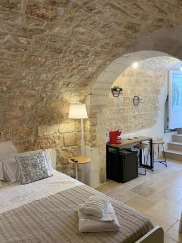 a bedroom with a bed and a stone wall at Atagio luxury room in Ostuni