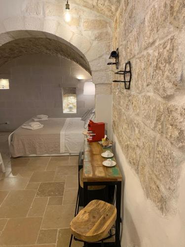 a room with a bed and a table in a stone wall at Atagio luxury room in Ostuni