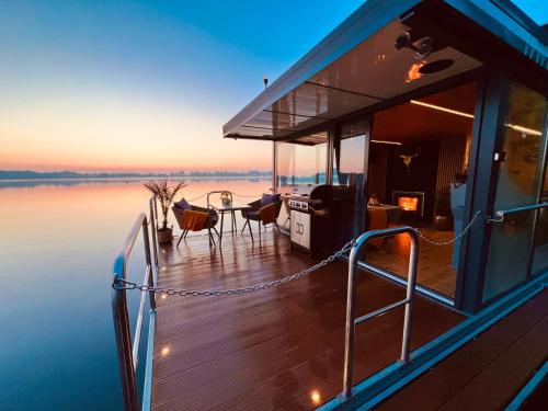 a boat deck with a table and chairs on the water at Seezeit- Schwielochsee- Hausboot in Schwielochsee