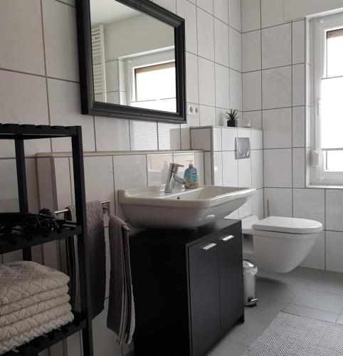 a bathroom with a sink and a toilet and a mirror at Ferienwohnung in der Stegwiese in Kaifenheim