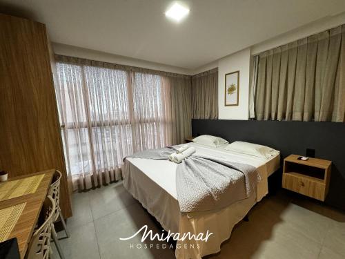 a bedroom with a bed and a large window at Get By Side - Jardim Oceania in Tambaú