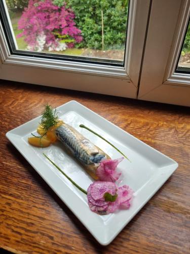 a white plate with a carrot and flowers on a table at La Villa Bois Joli HOTEL RESTAURANT in Bagnoles de l'Orne
