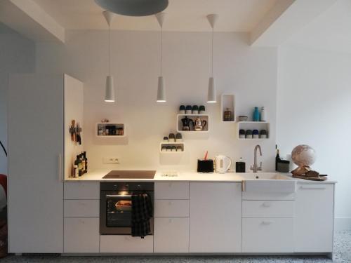 une cuisine avec des armoires blanches et un four dans l'établissement Les Sables, au Crotoy