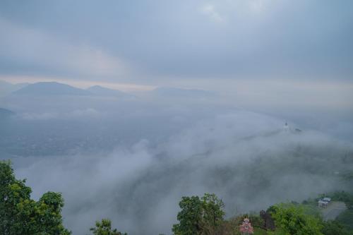 a foggy view of a body of water with trees at Raniban Retreat in Pokhara