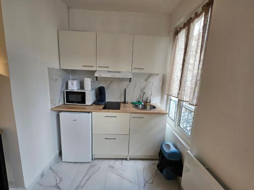 une petite cuisine avec des armoires blanches et un micro-ondes dans l'établissement Appartement a Paris Clichy, à Paris