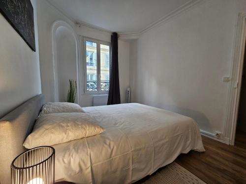 une chambre blanche avec un lit et une fenêtre dans l'établissement Appartement a Paris Clichy, à Paris