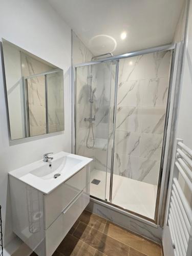 une salle de bain blanche avec une douche et un lavabo dans l'établissement Appartement a Paris Clichy, à Paris