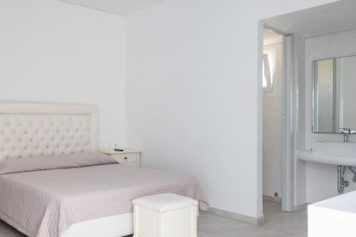 a white bedroom with a bed and a sink at La Villa Rooms in Mikonos