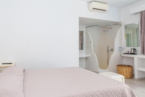 a white bedroom with a bed and a bathroom at La Villa Rooms in Mikonos