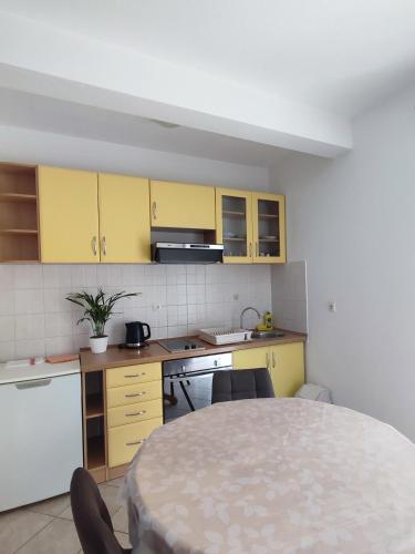 a small kitchen with yellow cabinets and a table at Ravkin Apartments in Zadar