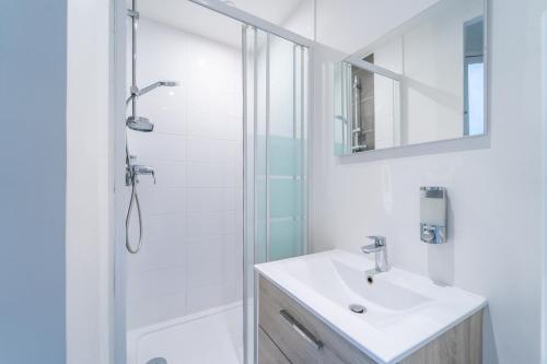 une salle de bain blanche avec un lavabo et une douche dans l'établissement GH Apartment Pasteur-Montparnasse, à Paris